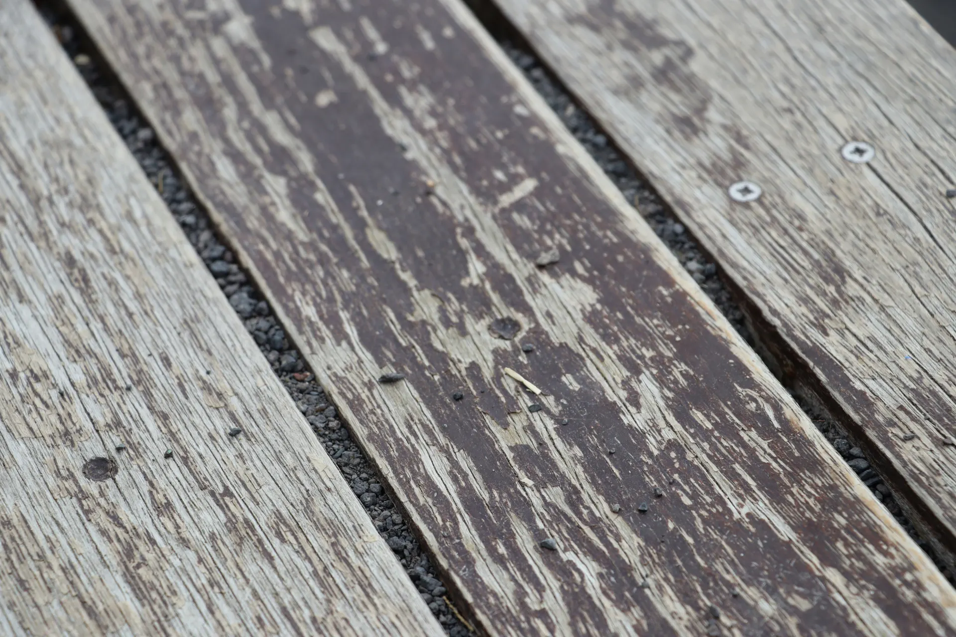 Stock photo: weathered grey deck boards with peeling dark stain and exposed screw heads